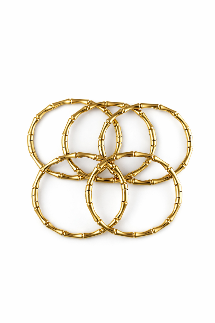 Set of gold bamboo bangles on a white background