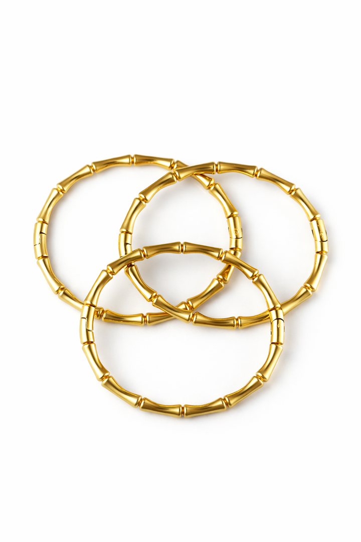 Set of gold bamboo bangle bracelets on a white background