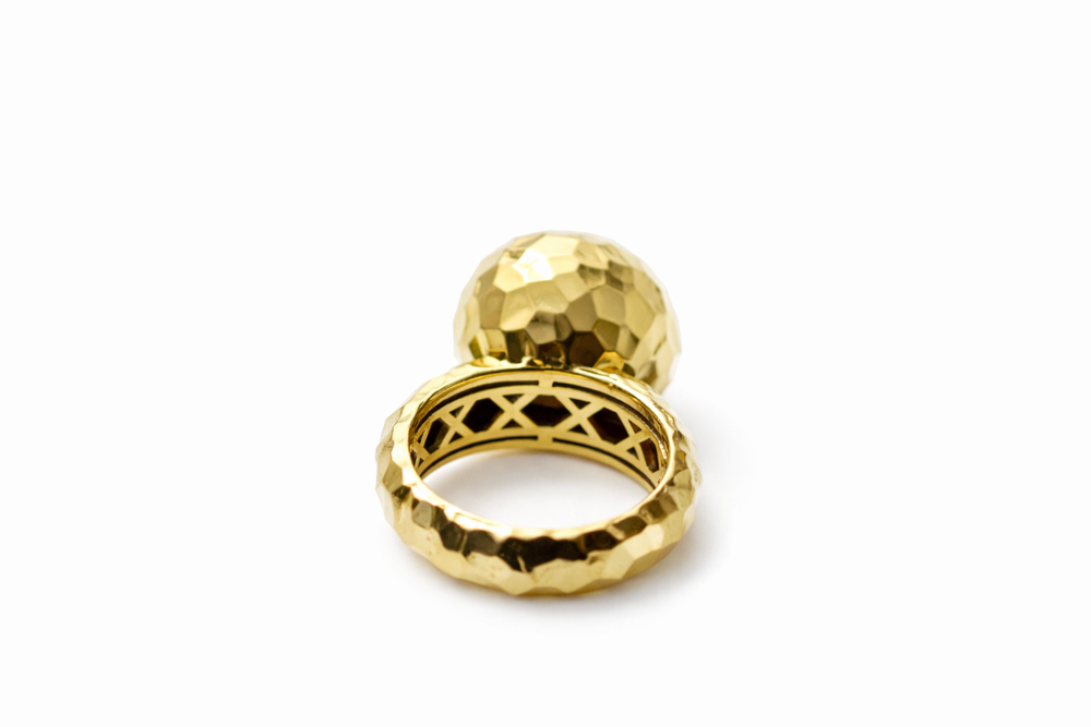 Gold ring with a textured design on a white background