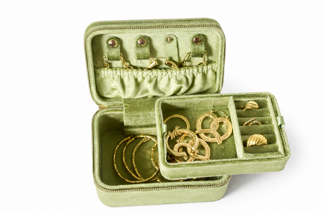 Green jewelry case with gold jewelry on a white background