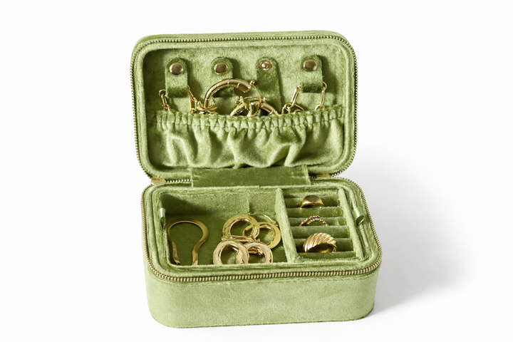 Green jewelry box with gold earrings on a white background